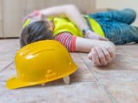 Injured worker had accident. man is lying on the floor. yellow helmet in front.