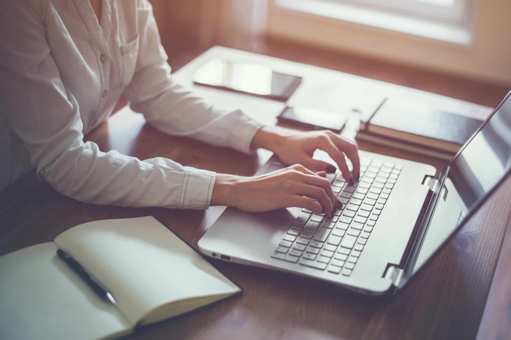 Woman working in home office hand on keyboard close up