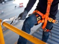 Construction worker use safety harness and safety line working on a new construction site project.