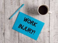 Conceptual hand writing showing work injury. business photo showcasing accident that occurred during and as result of working pastel colour paper and pen with coffee cup on wooden table.