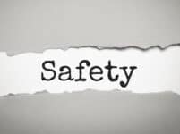 Safety Word Under Torn White Paper On Grey Background