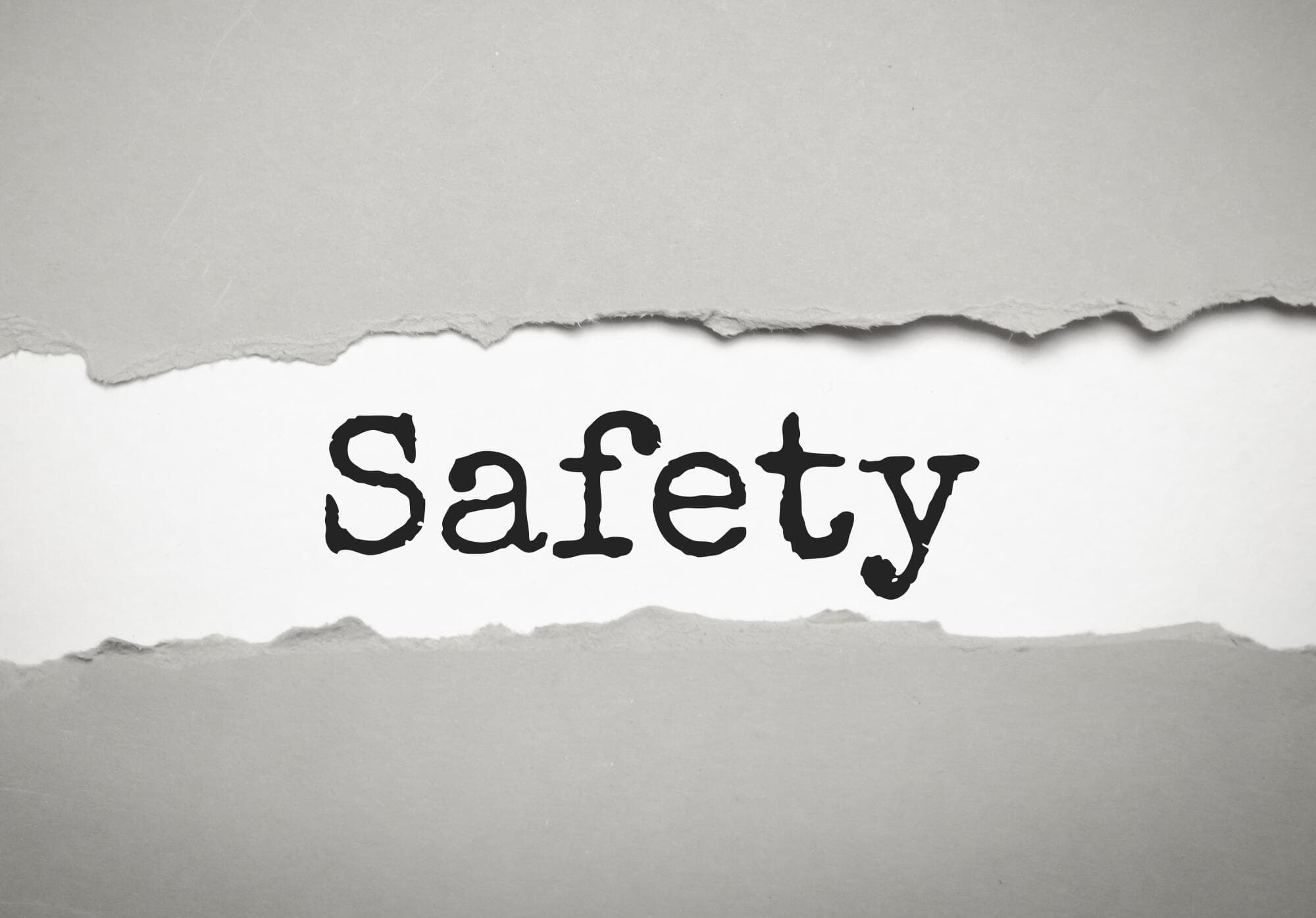 Safety Word Under Torn White Paper On Grey Background