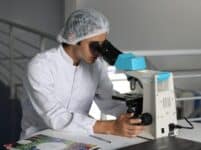 lab worker looking through microscope