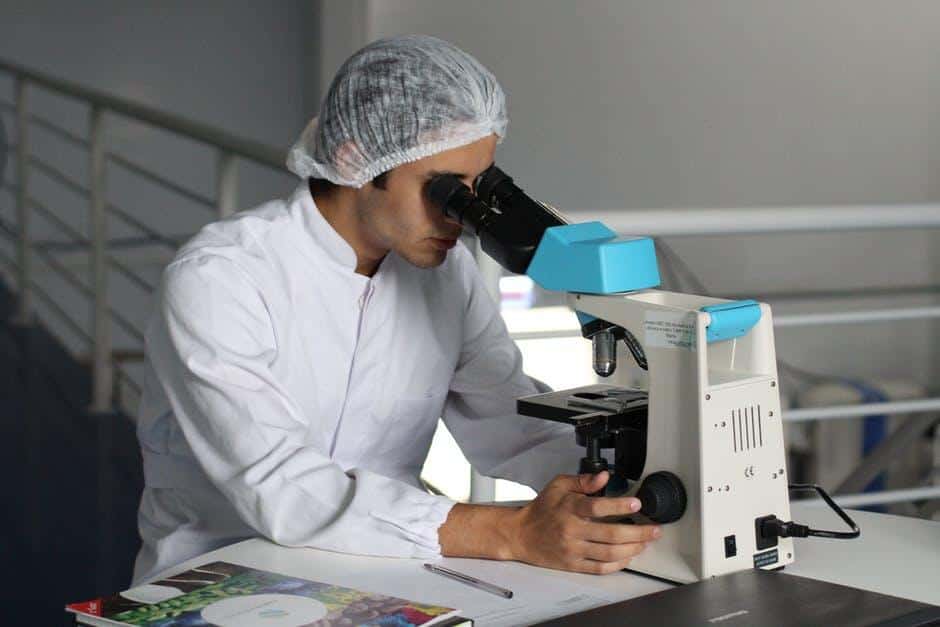 lab worker looking through microscope